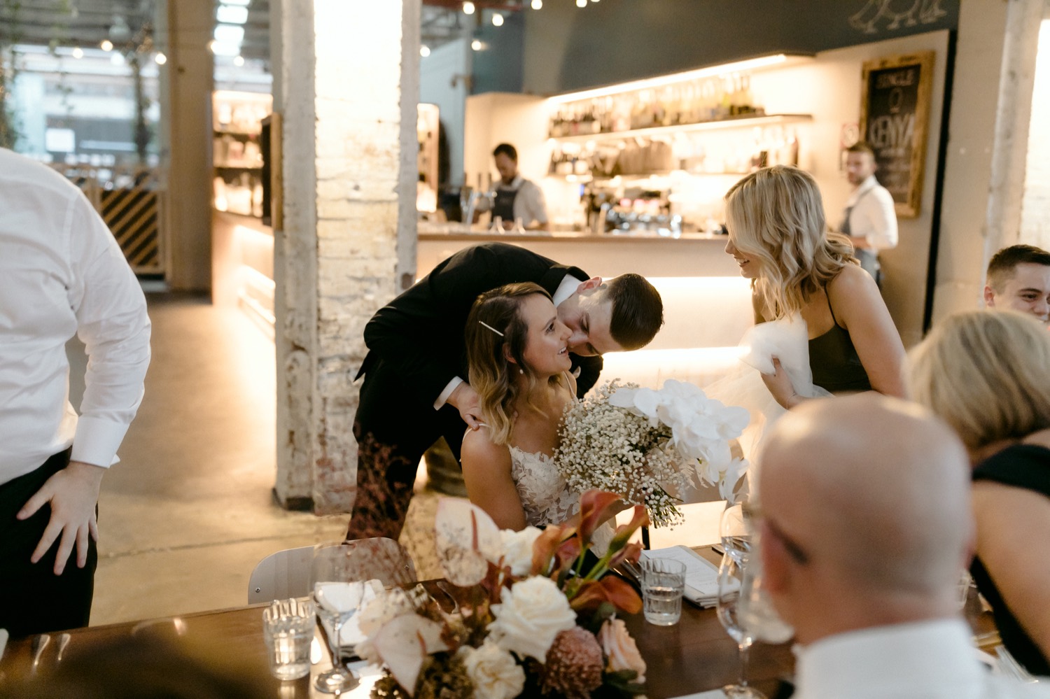 groom hugging a sat bride from behind as she laughs
