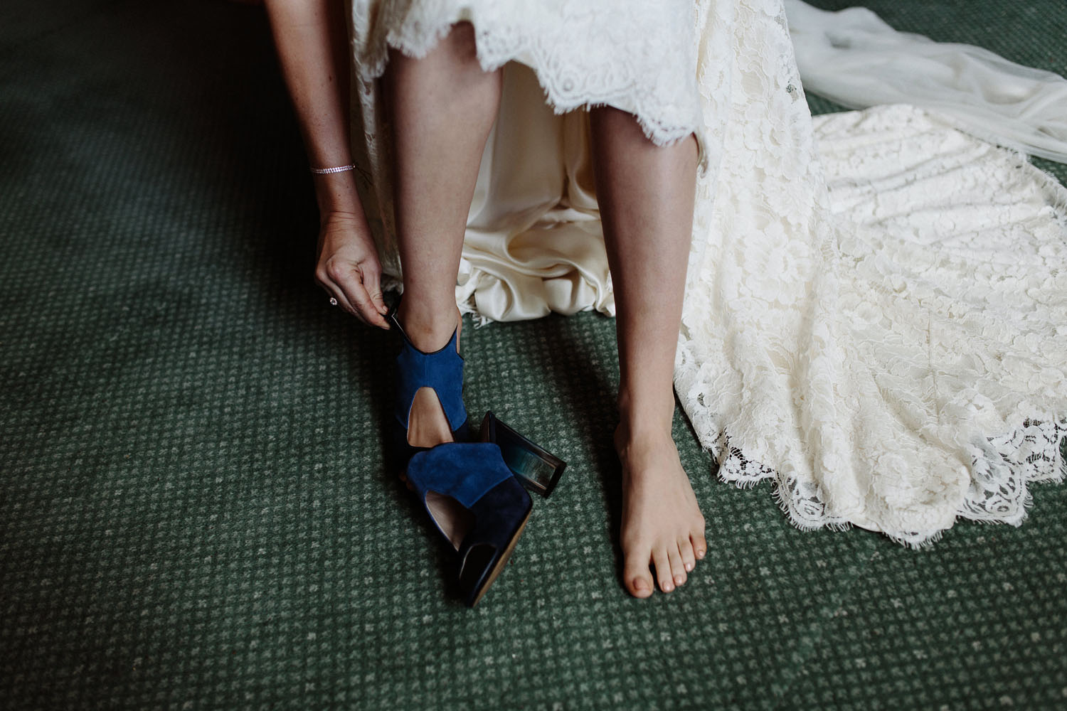 bride putting on blue wedding shoes