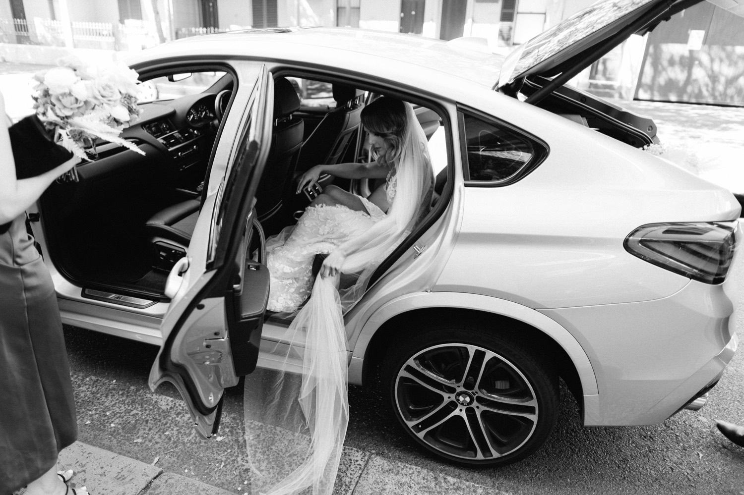 bride entering car with veil trailing behind her